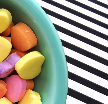 Schüssel mit bunten Zuckerherzen auf schwarz-weißem Hintergrund