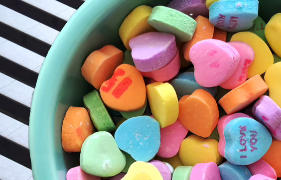 Schüssel mit bunten Zuckerherzen auf schwarz-weißem Hintergrund